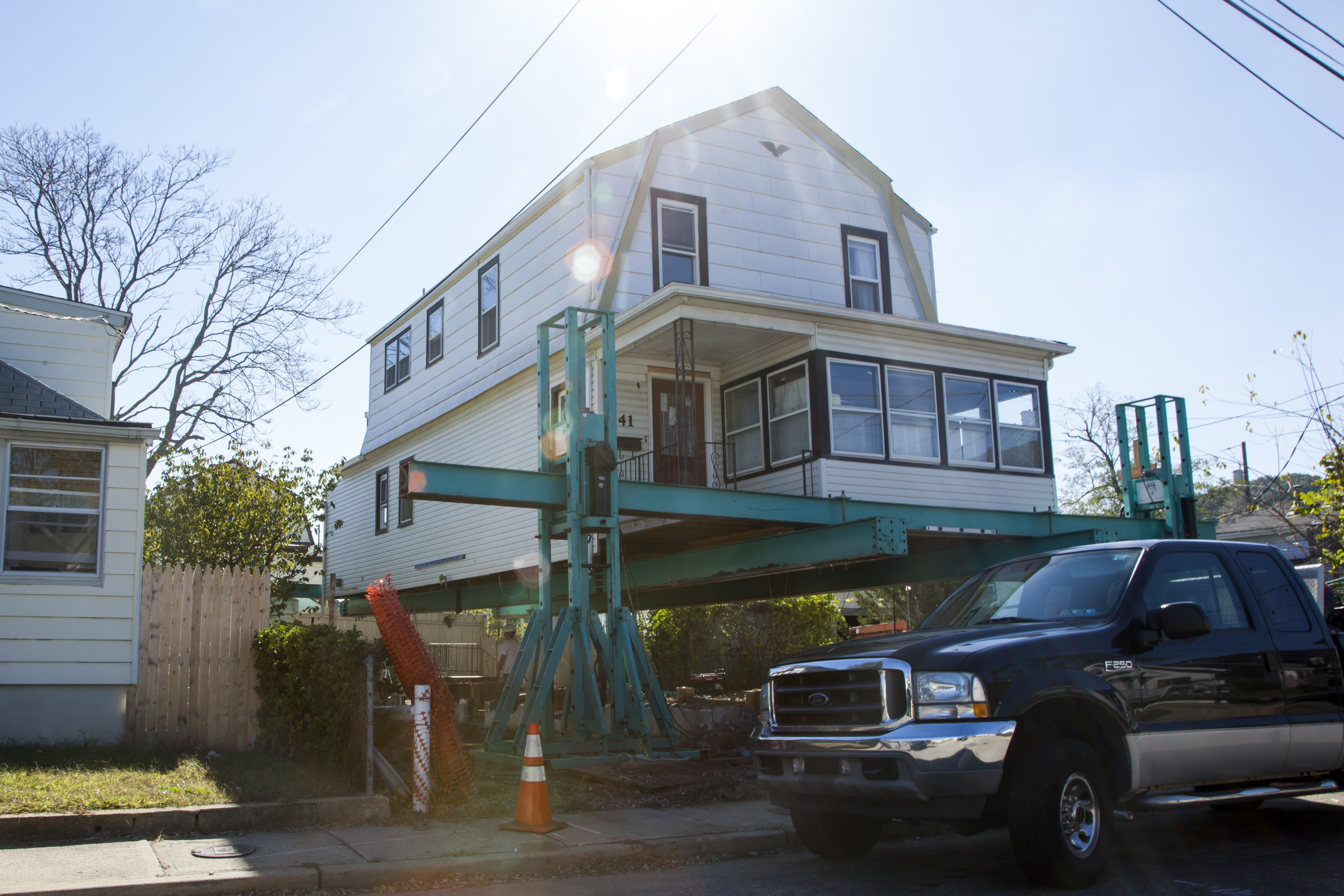 A house on a suburban street is raised off its foundation.