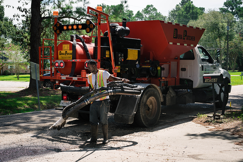 IBTS public works staff sprays cement onto the road to patch a hole.