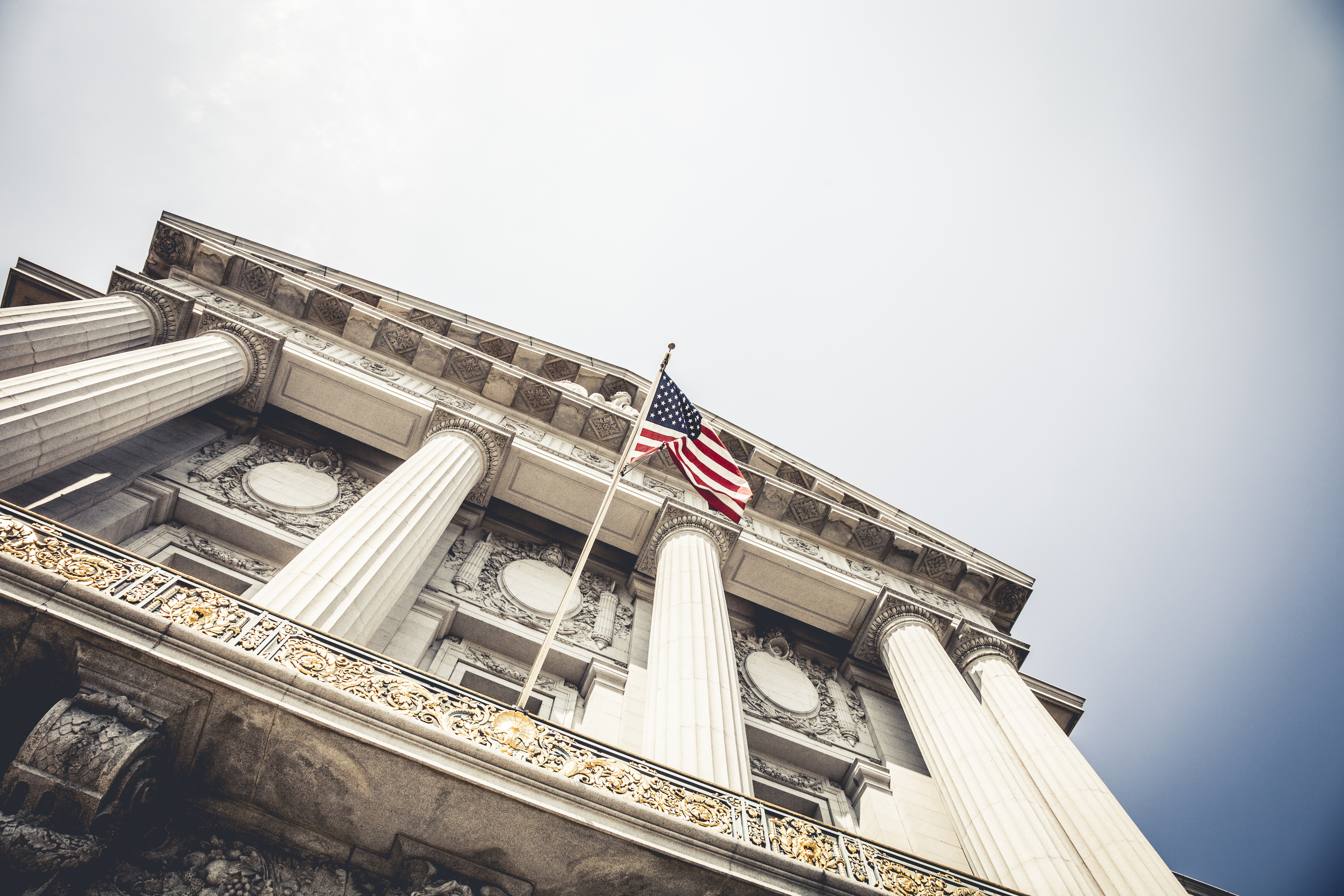 A City Hall entrance seen from below with a national flag.