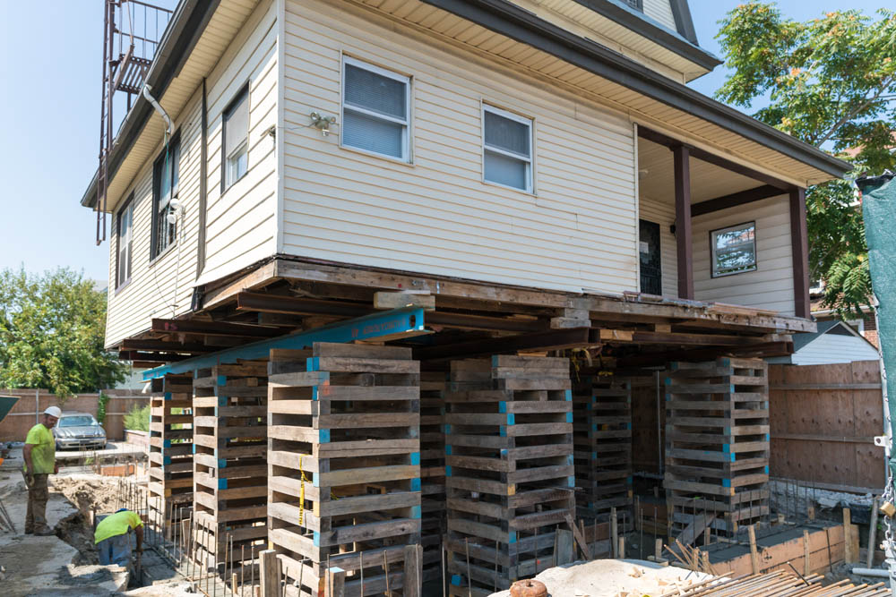 A house on stilts being raised after damaged in a flood.