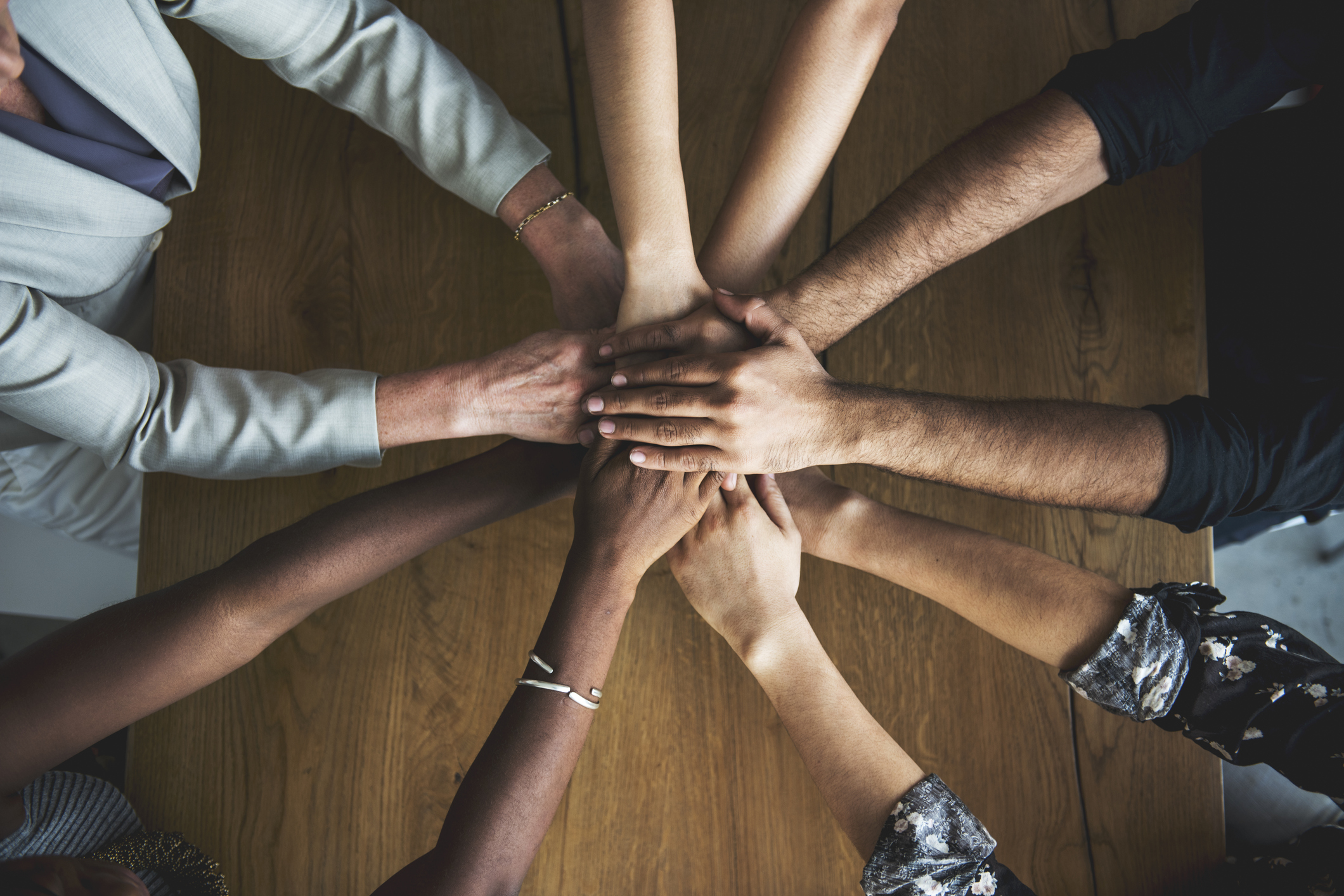 Photograph taken from above looking down on a multi-person handshake forming a circle.