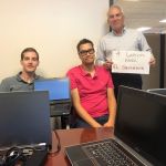 IBTS IT team members sit behind a desk.