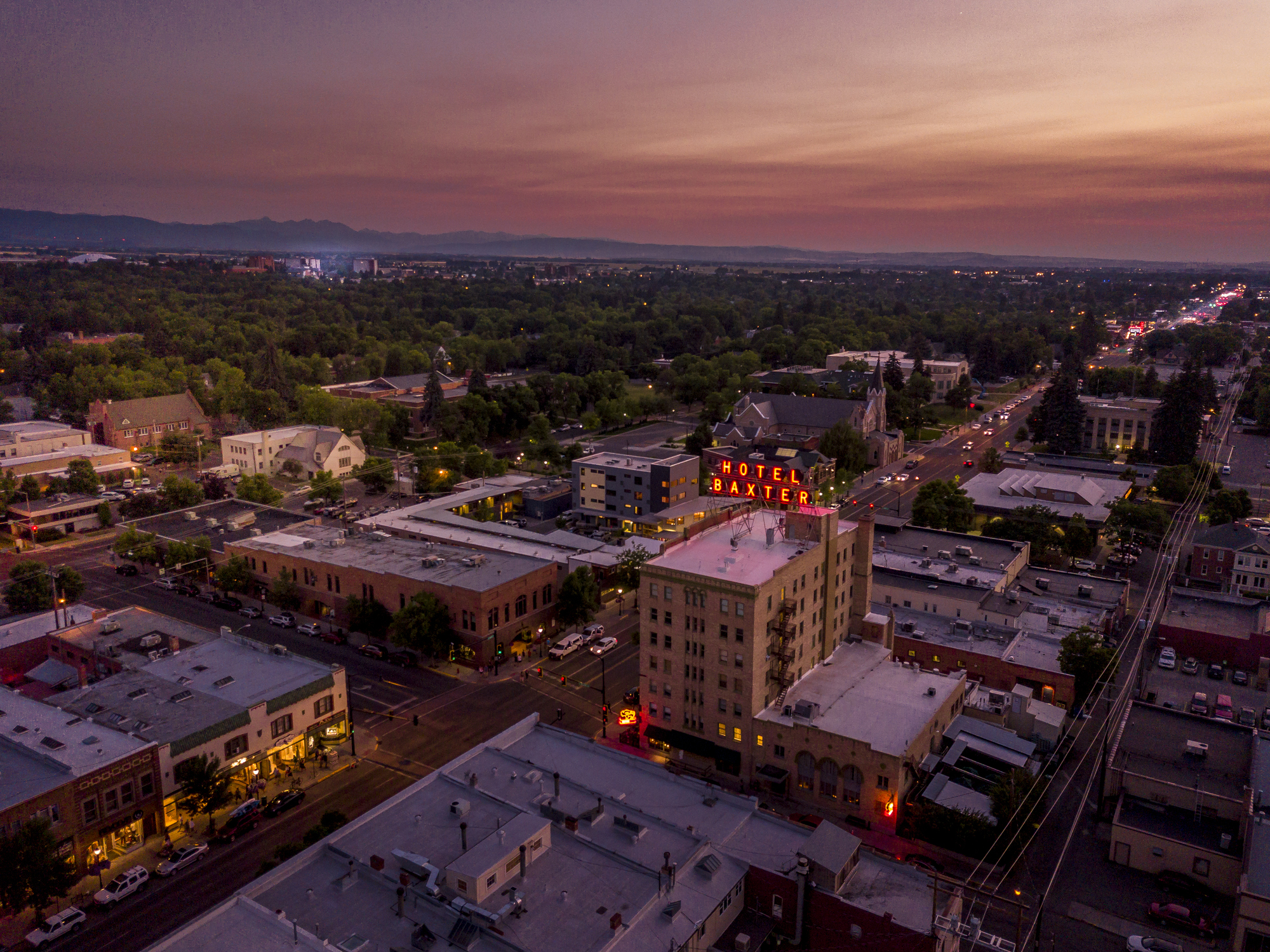 Aerial view of downtown Bozeman Montana at dusk. Main Street with lights twinkling from local businesses and vehicles.